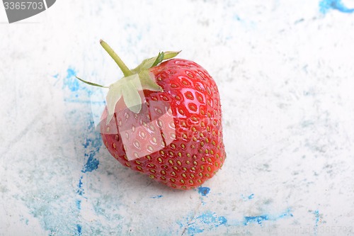 Image of Close-up detail of a fresh red strawberry with leaves