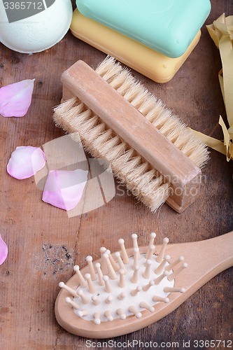 Image of hair brush, soap, comb, sea salt, spa stones and flower petals on wooden table