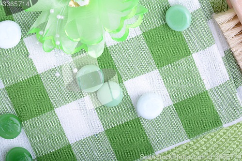 Image of spa settings, green towel with white and green spa stone, hairbrush