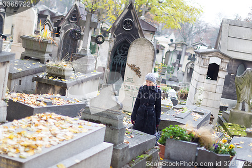 Image of Solitary woman visiting relatives grave.