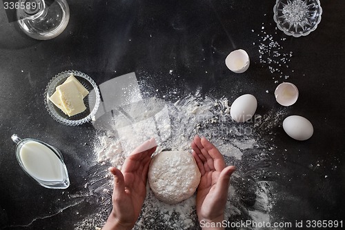 Image of Woman\'s hands knead dough on table with flour