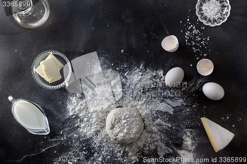 Image of Dough on black table with flour and ingredients