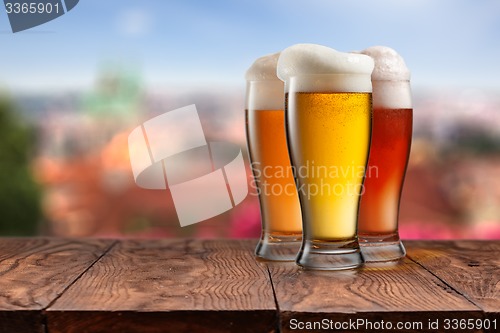 Image of Glasses of different beer on wooden table against Prague