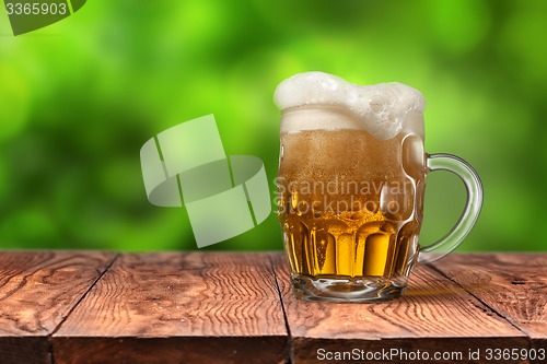 Image of Beer in glass on wooden table against green