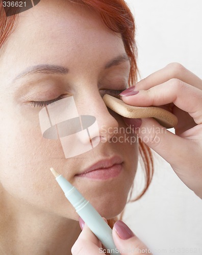 Image of beautician is doing make-up to red-haired woman