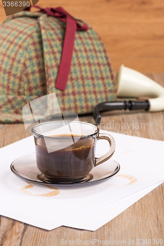 Image of Coffee cup, paper sheets and detective hat