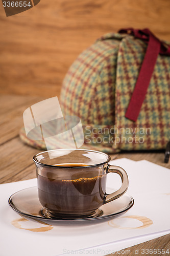 Image of Coffee cup, paper sheets and detective hat