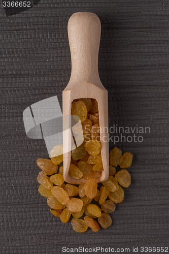 Image of Wooden scoop with golden raisins