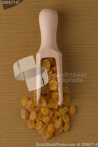 Image of Wooden scoop with golden raisins