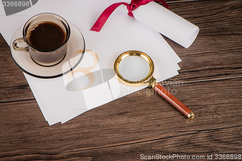 Image of Coffee cup, paper sheets and detective hat