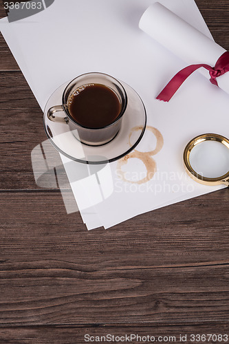 Image of Coffee cup, paper sheets and detective hat