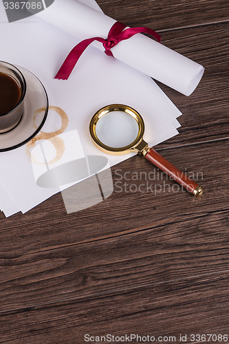 Image of Coffee cup, paper sheets and detective magnifying glass