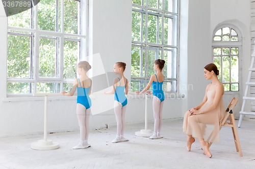 Image of Three little ballerinas dancing with personal ballet teacher in dance studio