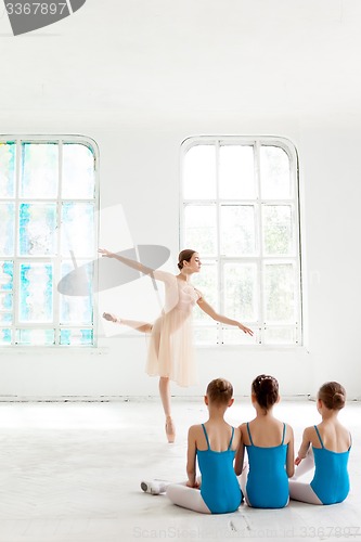 Image of Three little ballerinas dancing with personal ballet teacher in dance studio