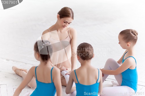 Image of Three little ballerinas dancing with personal ballet teacher in dance studio