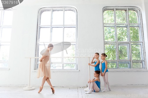 Image of Three little ballerinas dancing with personal ballet teacher in dance studio