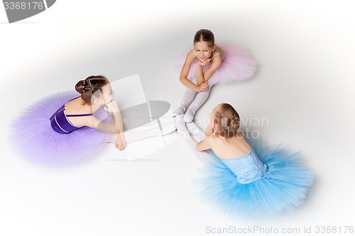 Image of Three little ballet girls sitting in tutu and posing together