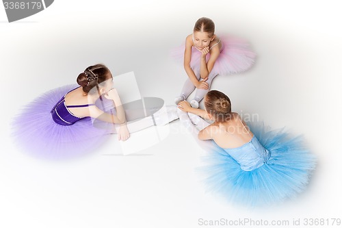 Image of Three little ballet girls sitting in tutu and posing together