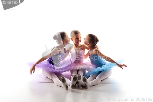Image of Three little ballet girls sitting in tutu and posing together