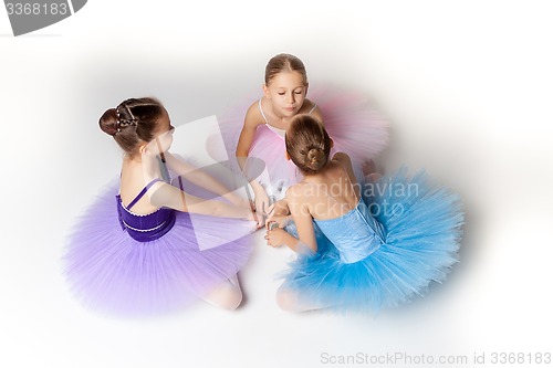 Image of Three little ballet girls sitting in tutu and posing together