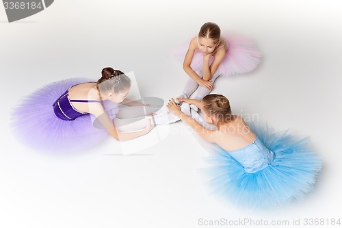 Image of Three little ballet girls sitting in tutu and posing together