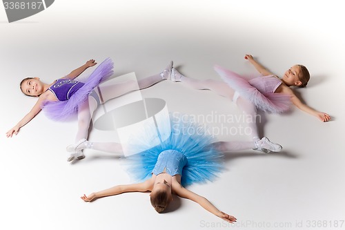 Image of Three little ballet girls in tutu lying and posing together