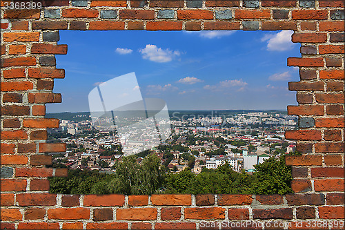 Image of broken wall from red brick and view to the city