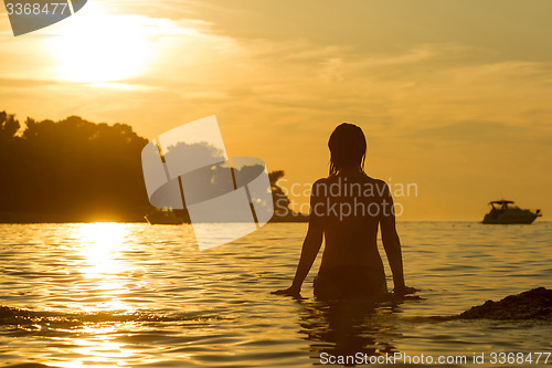 Image of Woman standing in shallow at sunset