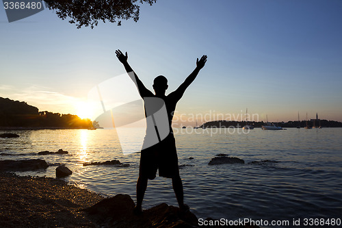 Image of Man saluting sun at sea