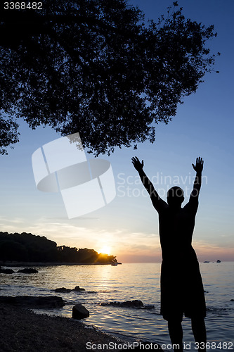 Image of Man saluting sun at Adriatic sea