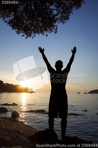 Image of Man saluting sun on shore