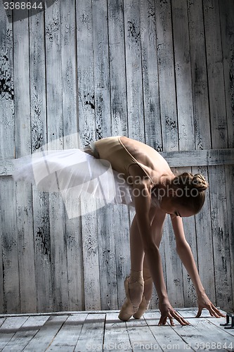 Image of Ballerina dressed in white tutu makes lean forward