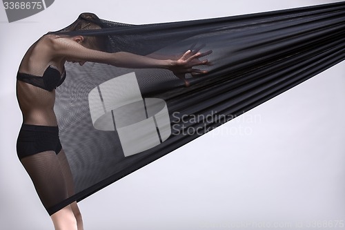 Image of Slim dancer plays with black mesh fabric