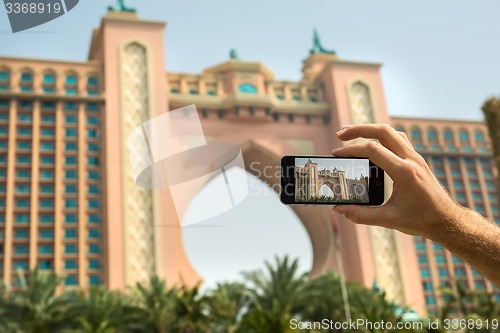 Image of Hand tourist takes a picture of the hotel Atlantis Dubai on mobi