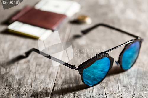 Image of Stylish sunglasses with blue tinted mirror on textured wooden ba