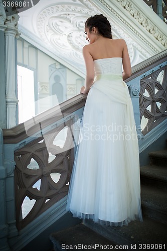 Image of Elegant bride in a white dress standing on the stairs