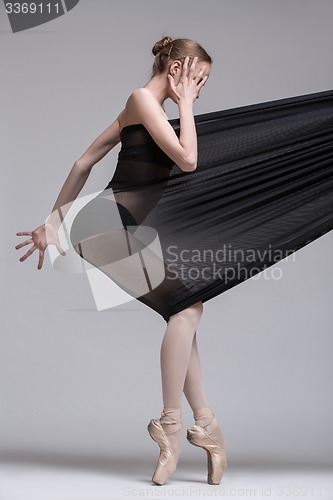 Image of Slim dancer plays with black mesh fabric