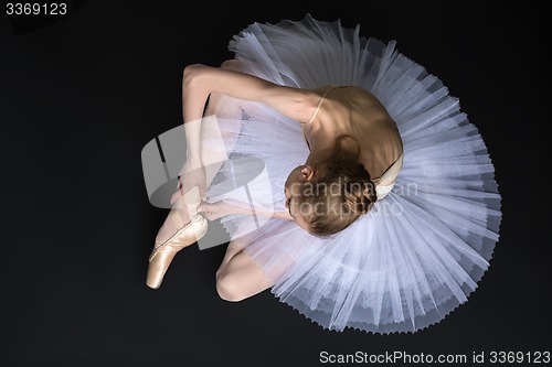 Image of Young ballet dancer tying pointe sitting on the floor