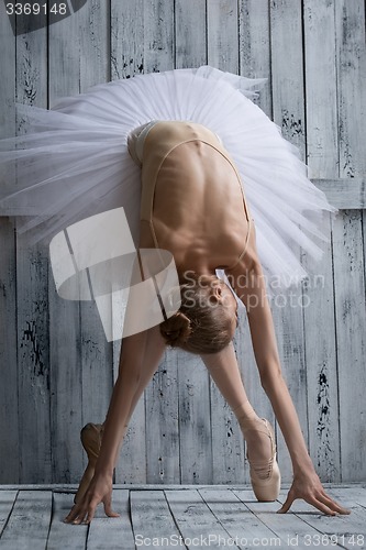 Image of Ballerina dressed in white tutu makes lean forward