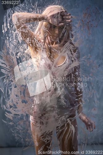 Image of Portrait of seminude blonde through the glass smeared pink clay