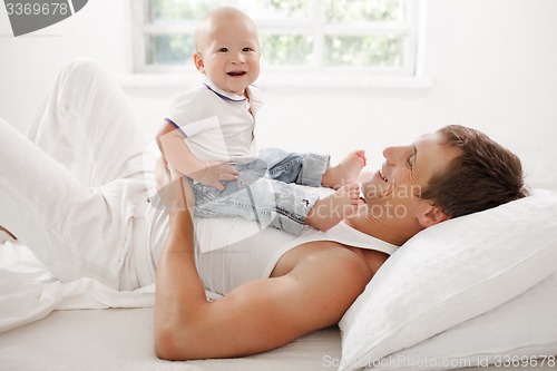 Image of young father with his nine months old son on the bed at home