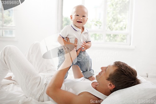 Image of young father with his nine months old son on the bed at home