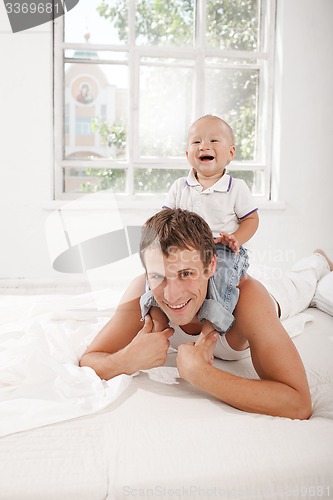 Image of young father with his nine months old son on the bed at home