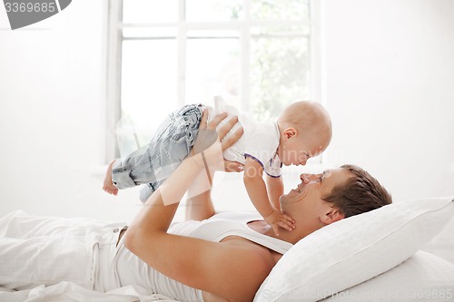 Image of young father with his nine months old son on the bed at home