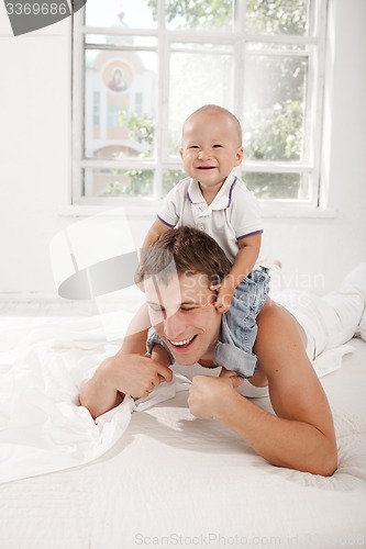 Image of young father with his nine months old son on the bed at home