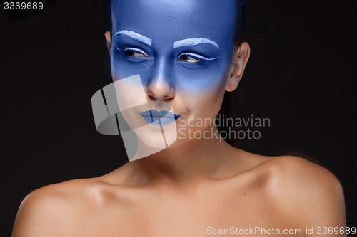 Image of Portrait of a woman who is posing covered with blue paint