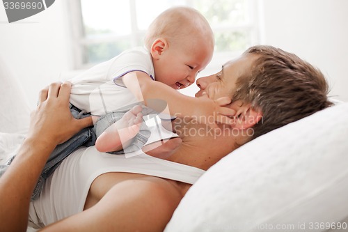 Image of young father with his nine months old son on the bed at home