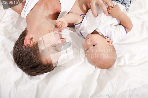 Image of young father with his nine months old son on the bed at home