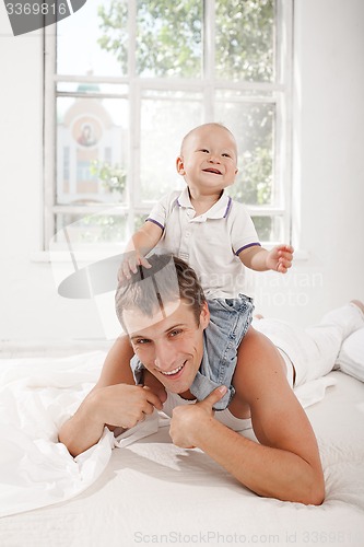 Image of young father with his nine months old son on the bed at home