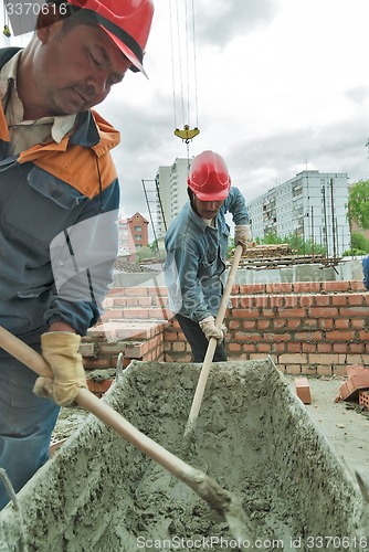 Image of Workers knead solution for bricklayers